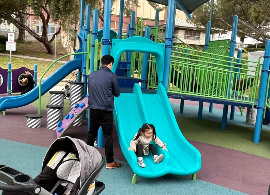 TVC Studios Little girl sliding down slide at the park